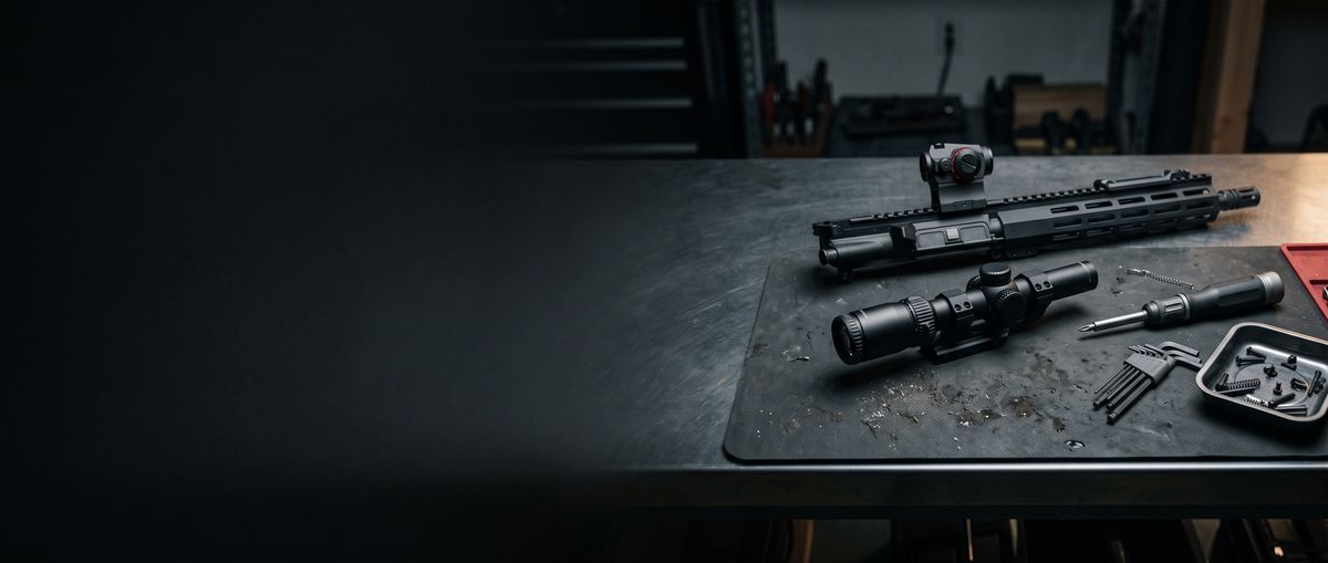 Rifle upper, scope and tools laid out on a workbench mat