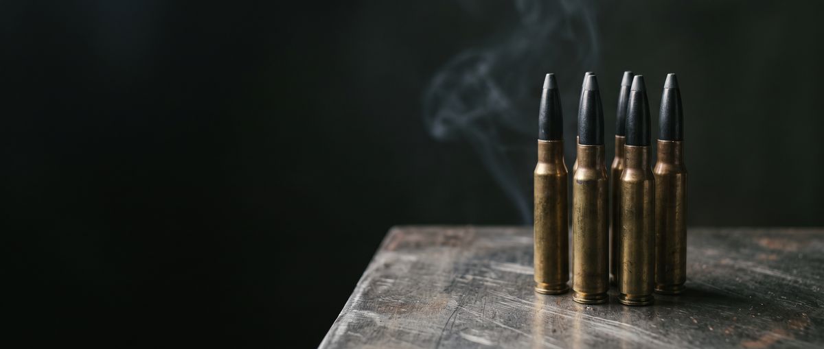 Five subsonic rifle cartridges on a worn wooden table
